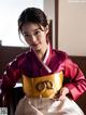 A woman in a red and white hanbok sitting on a chair.